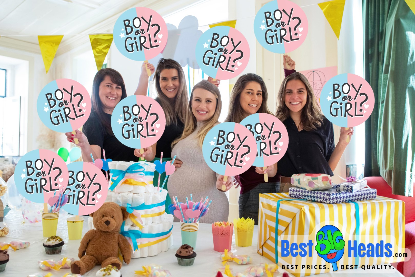 A group of five smiling women at a baby shower holding up "Boy or Girl?" big head cutouts, celebrating the upcoming arrival. The table in front of them is decorated with baby shower essentials, including cupcakes, a diaper cake, colorful straws, and a teddy bear. The atmosphere is festive with yellow and blue decorations, and a large wrapped gift is on the side. The logo for Best Big Heads™ is displayed in the bottom right corner, showcasing the source of the custom big head cutouts.